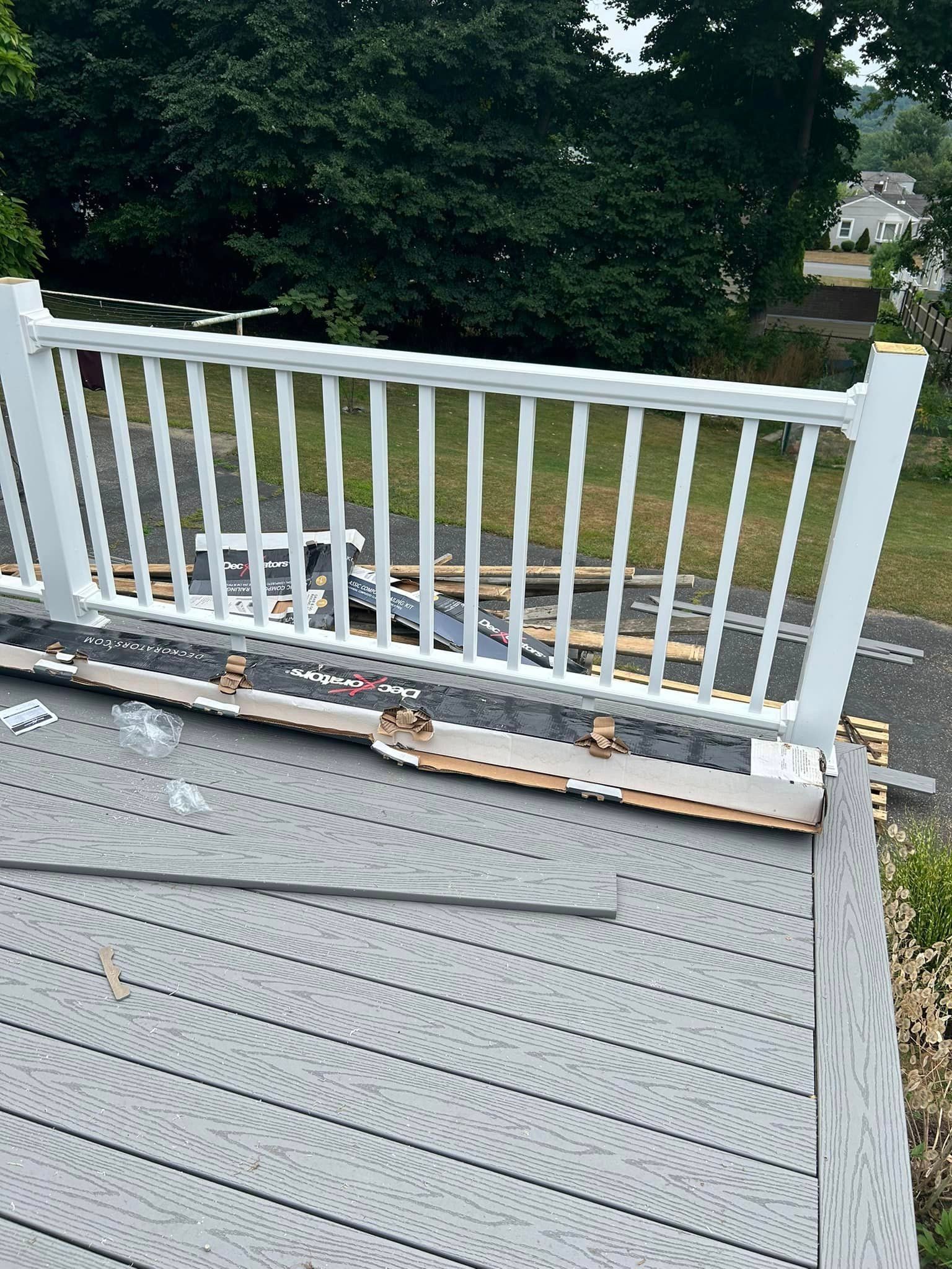 A white railing is sitting on top of a wooden deck.