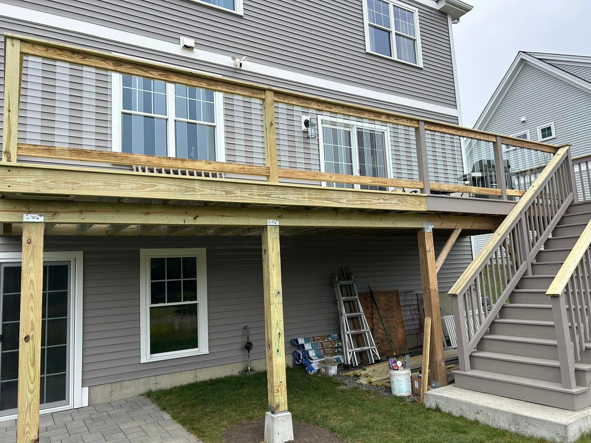 A deck with stairs leading up to it is being built on the back of a house.