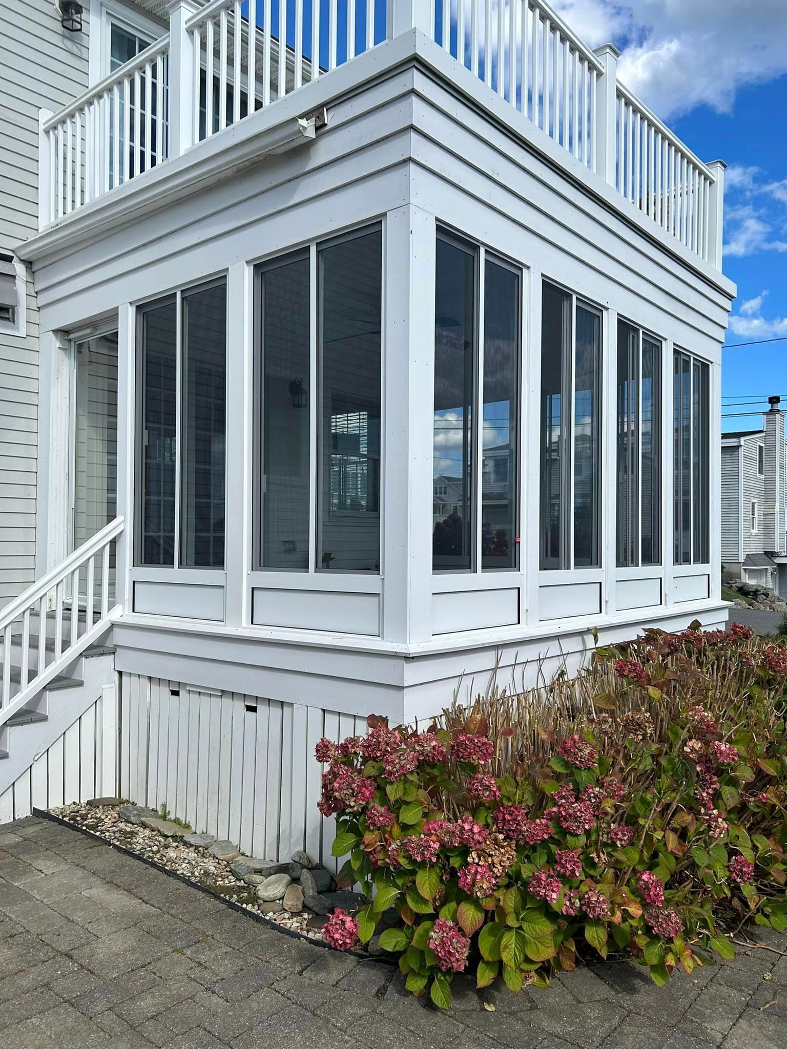 A white house with a screened in porch and stairs.