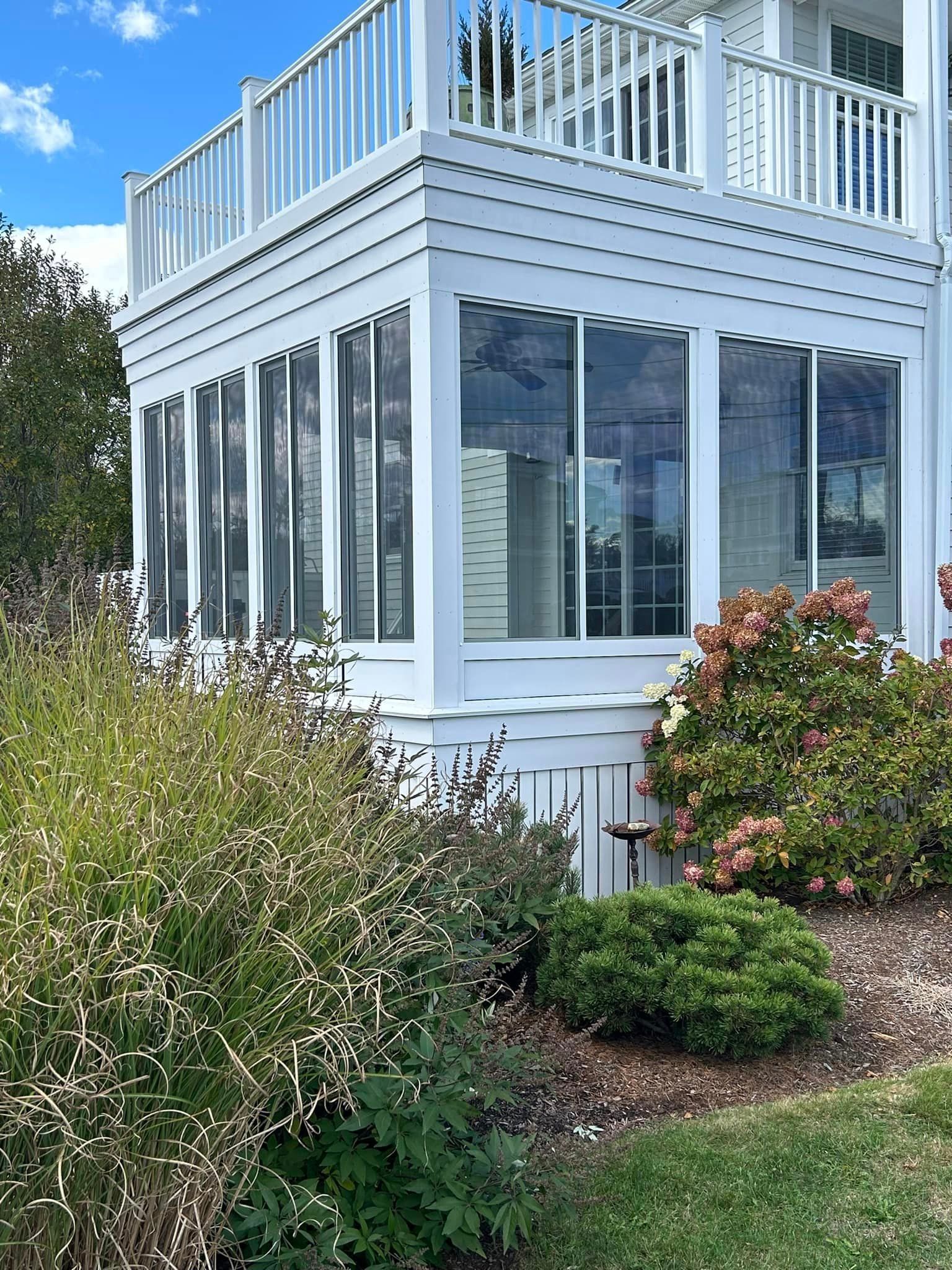 A white house with a large porch and lots of windows.