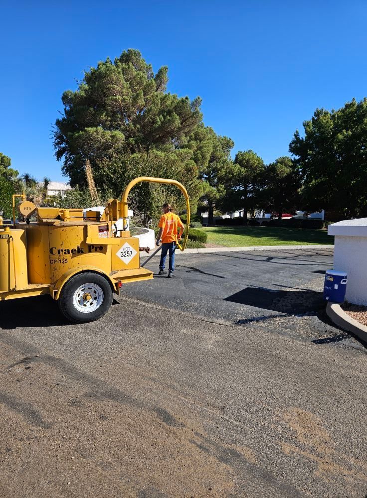 Worker in orange vest beside a yellow wood chipper on a sunny street near trees