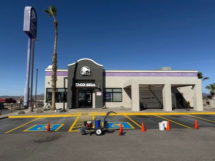 Taco Bell storefront with parking lot, blue sky, and bright traffic cones in front