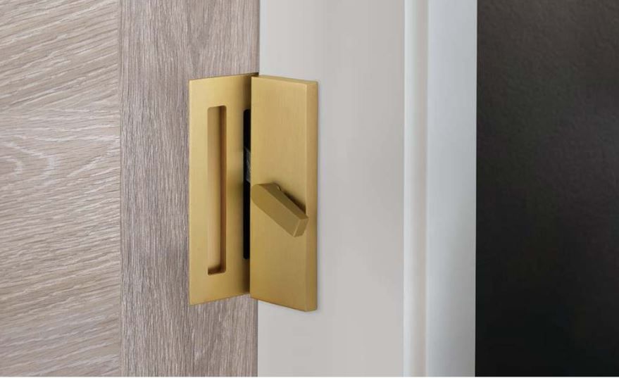 Gold door handle on white door, partially open, adjacent to wood paneling.