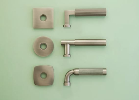 Three modern silver door handles with matching plates, arranged on a mint-green background.
