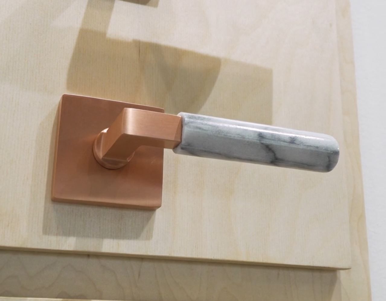 Copper door handle with marble grip on a wooden door.