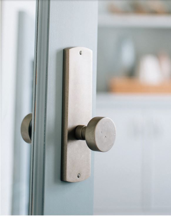 Door with silver handle and backplate, blue door frame, slightly open to a blurred white interior.