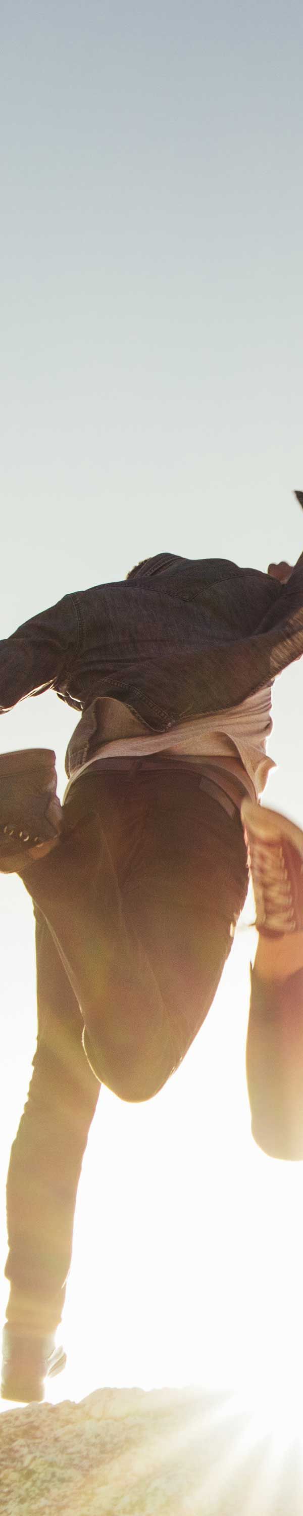 Person in mid-air performing a stunt. Bright sunlight washes out the bottom of the photo.