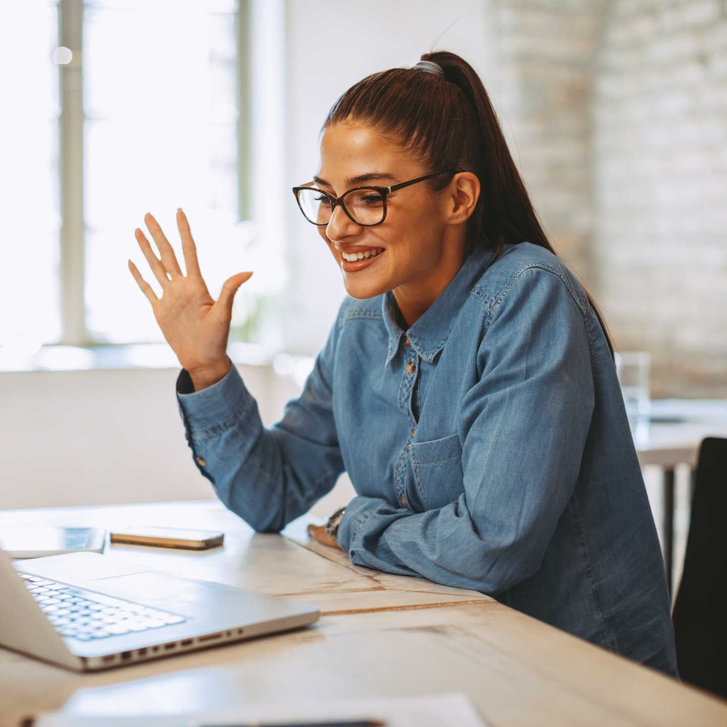 Woman exercising with dumbbells indoors, smiling. She wears gray sweats. Bright green weights.