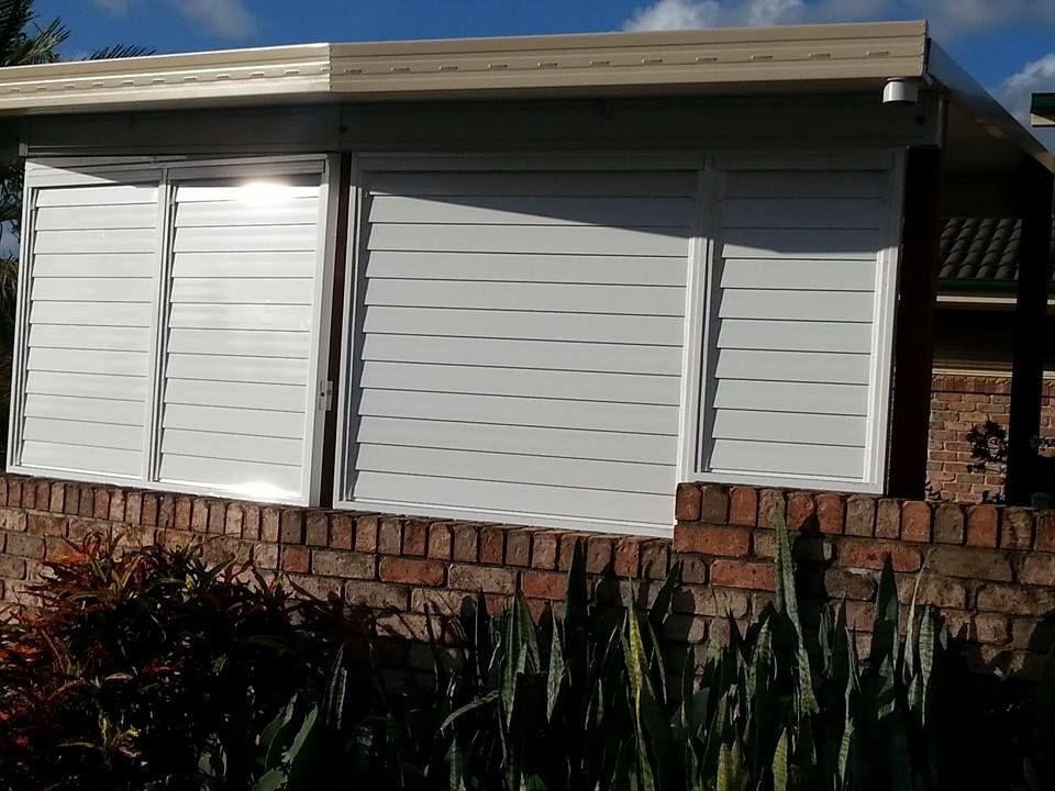 A House With White Shutters On The Windows And A Brick Wall — Boambee Home Improvements in Bellingen, NSW