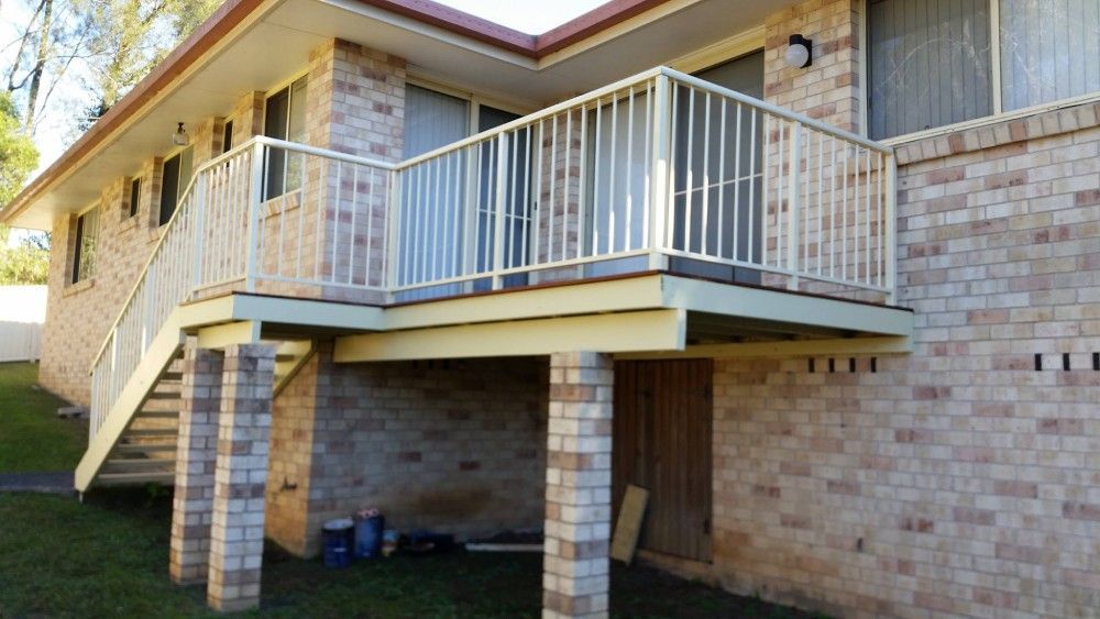 A Brick House With A Balcony And Stairs On The Side Of It — Boambee Home Improvements in Urunga, NSW