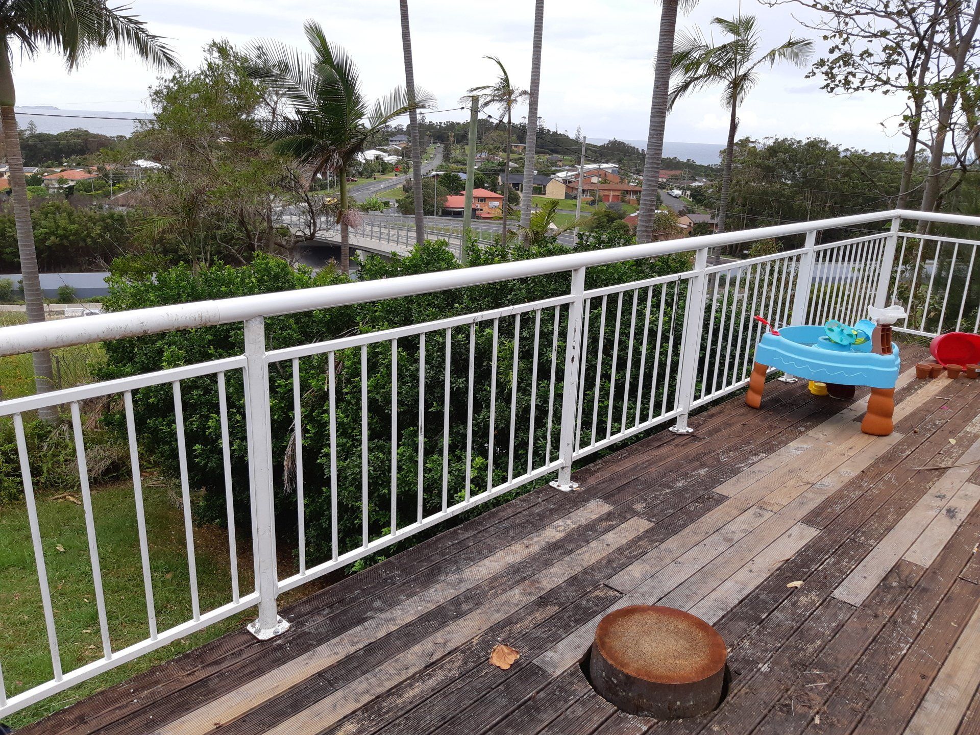 A Wooden Deck With A White Railing And A Table On It — Boambee Home Improvements in Coffs Harbour, NSW