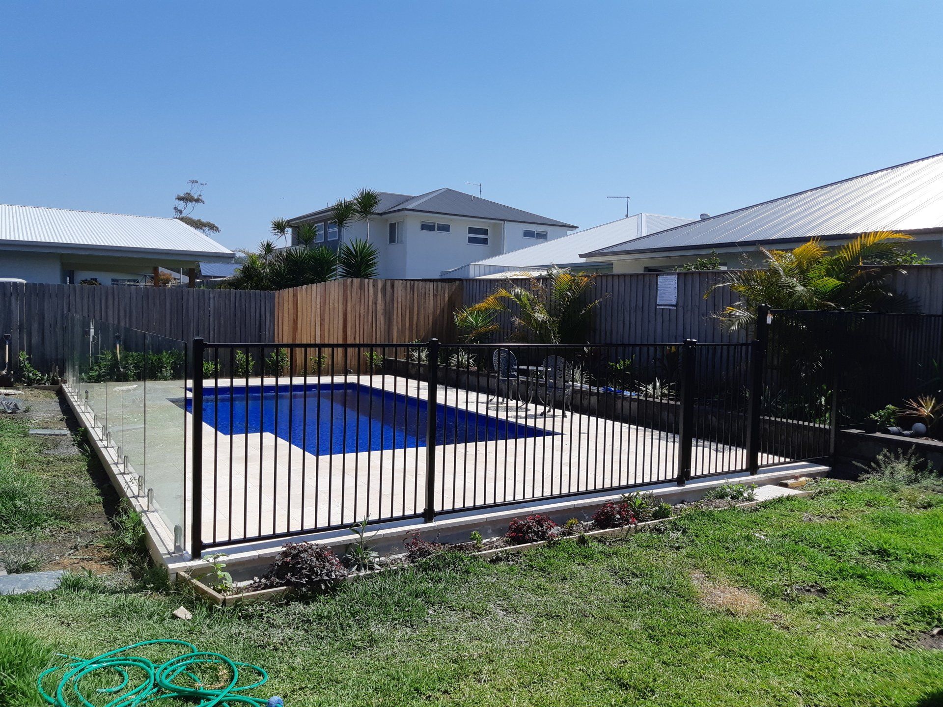 A Fence Surrounds A Swimming Pool In A Backyard — Boambee Home Improvements in Coffs Harbour, NSW