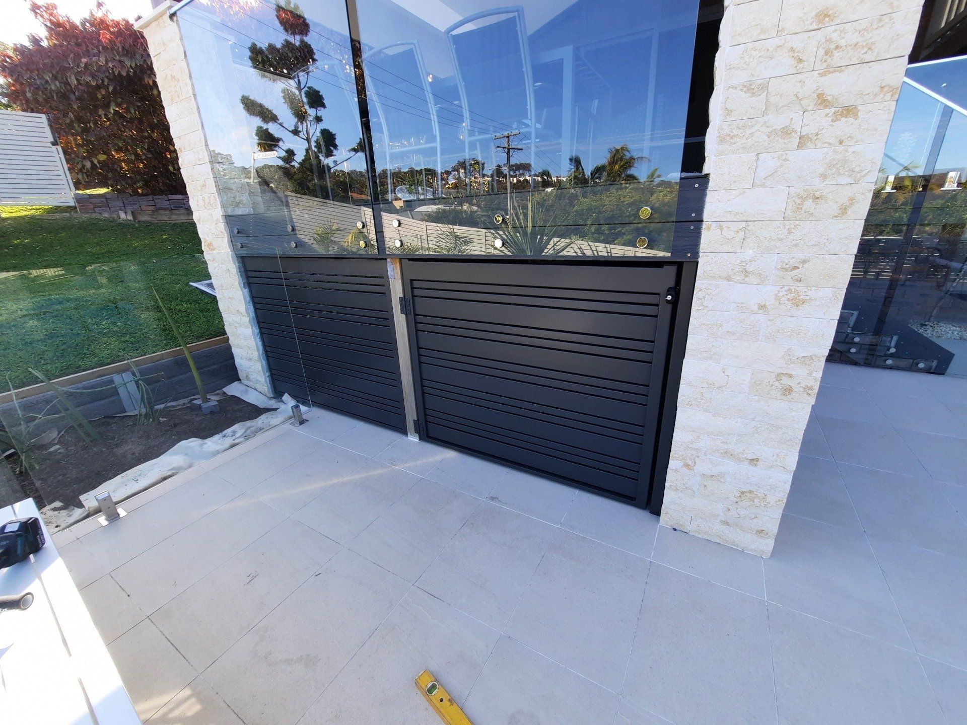 A Black Fence Is Being Installed On The Side Of A Building — Boambee Home Improvements in Coffs Harbour, NSW