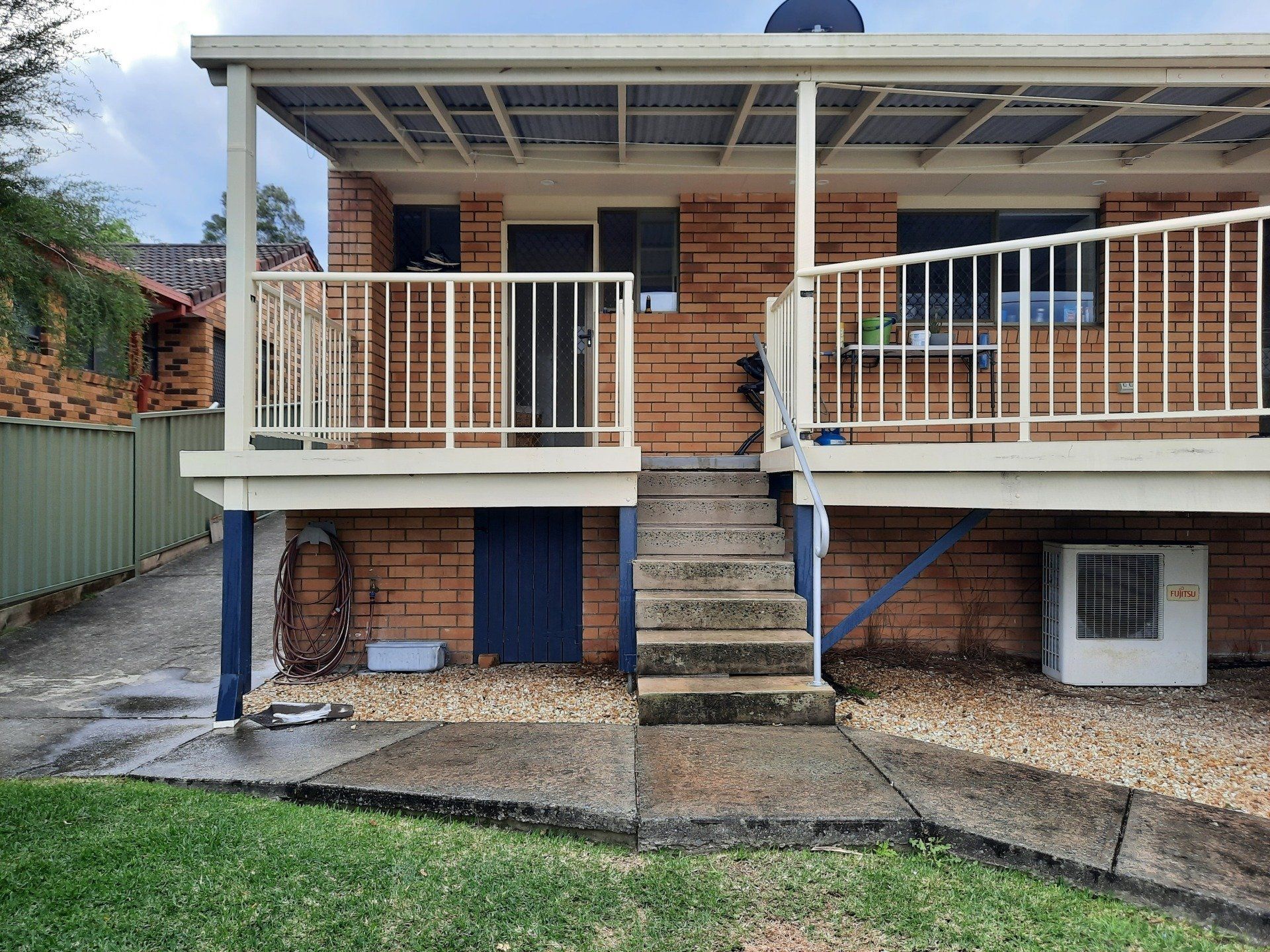 A Brick House With A Balcony And Stairs — Boambee Home Improvements in Coffs Harbour, NSW