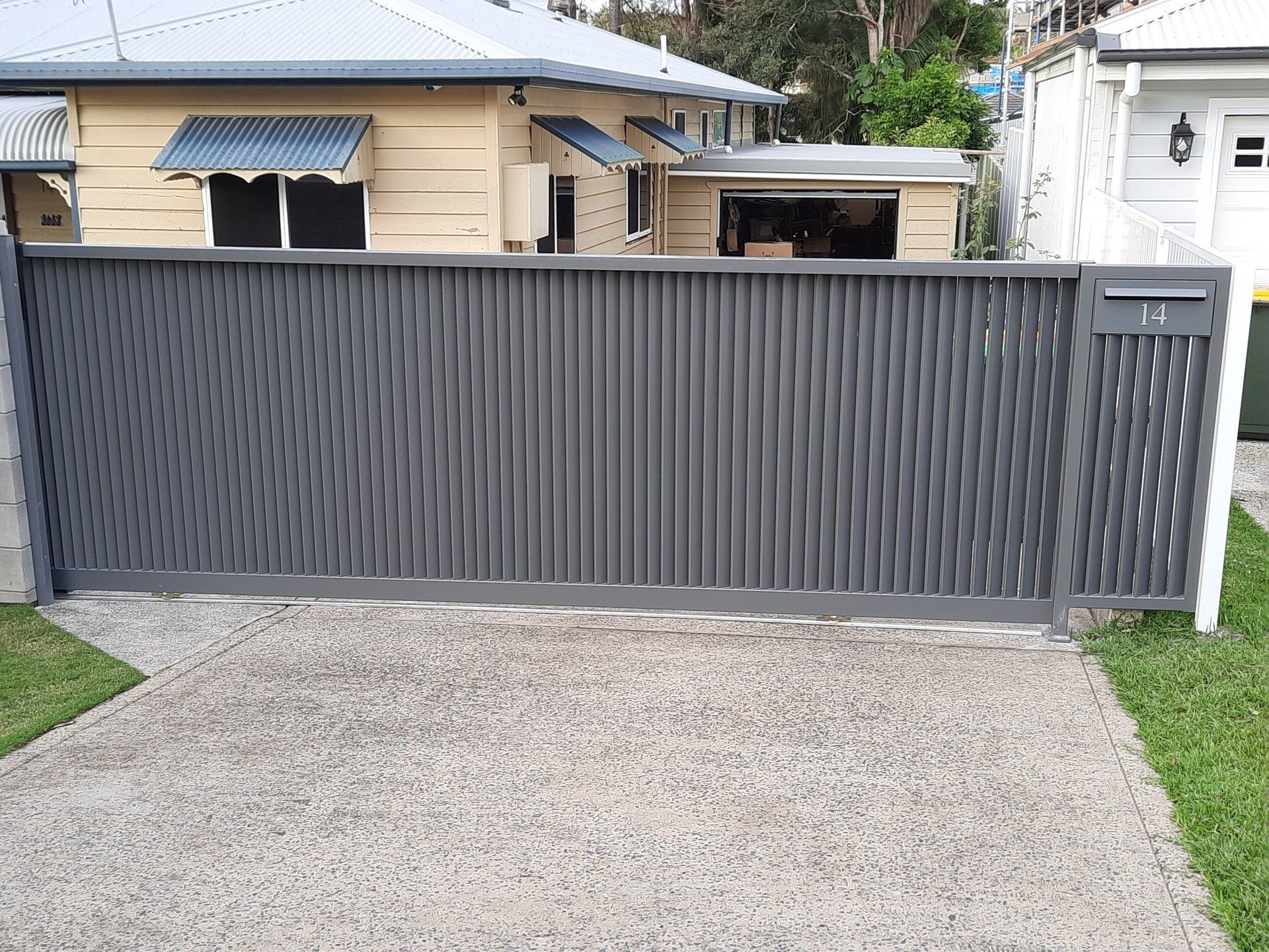 A Sliding Gate Is Sitting In Front Of A House — Boambee Home Improvements in Coffs Harbour, NSW