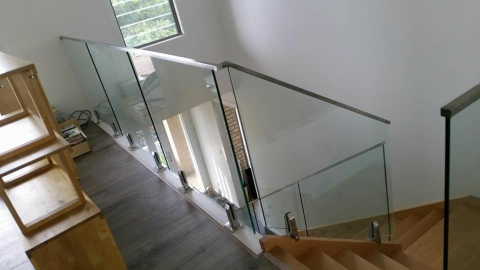A Wooden Staircase With A Glass Railing In A House — Boambee Home Improvements in Woolgoolga, NSW