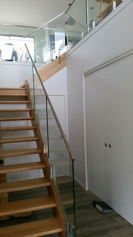 A Wooden Staircase With A Glass Railing In A House — Boambee Home Improvements in Woolgoolga, NSW
