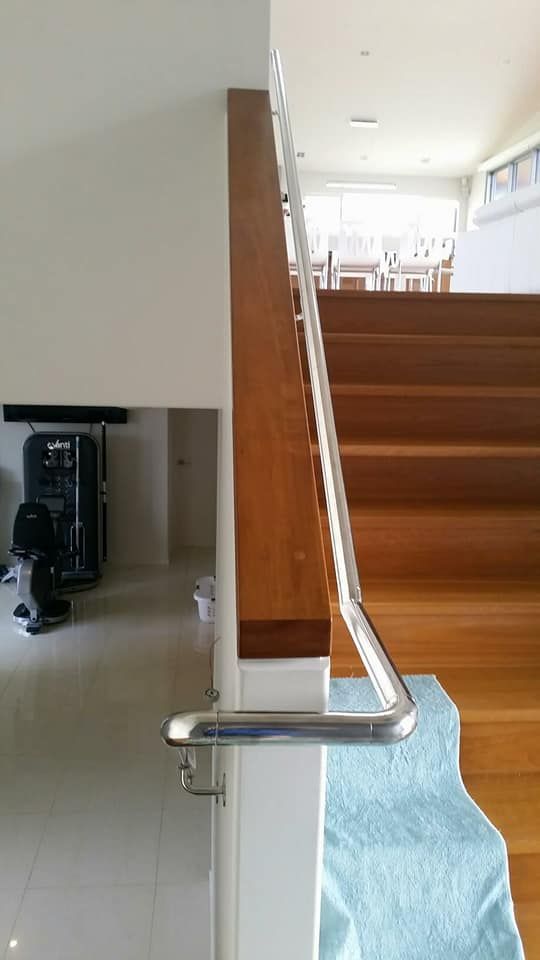 A Wooden Staircase With A Stainless Steel Railing In A House — Boambee Home Improvements in Coffs Harbour, NSW