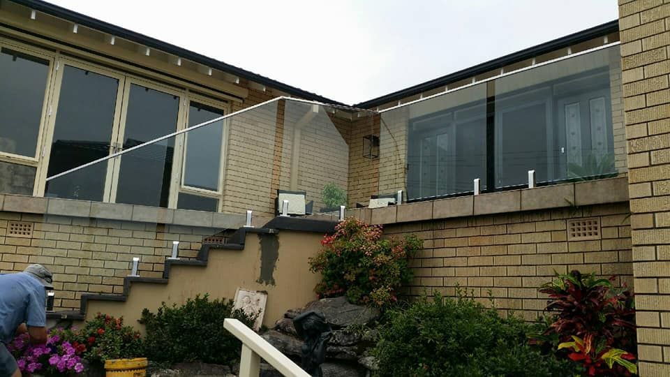 A Brick House With A Glass Railing On The Side Of It — Boambee Home Improvements in Sawtell, NSW