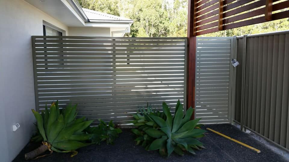 A Fence With A Gate And Plants In Front Of A House — Boambee Home Improvements in Macksville, NSW