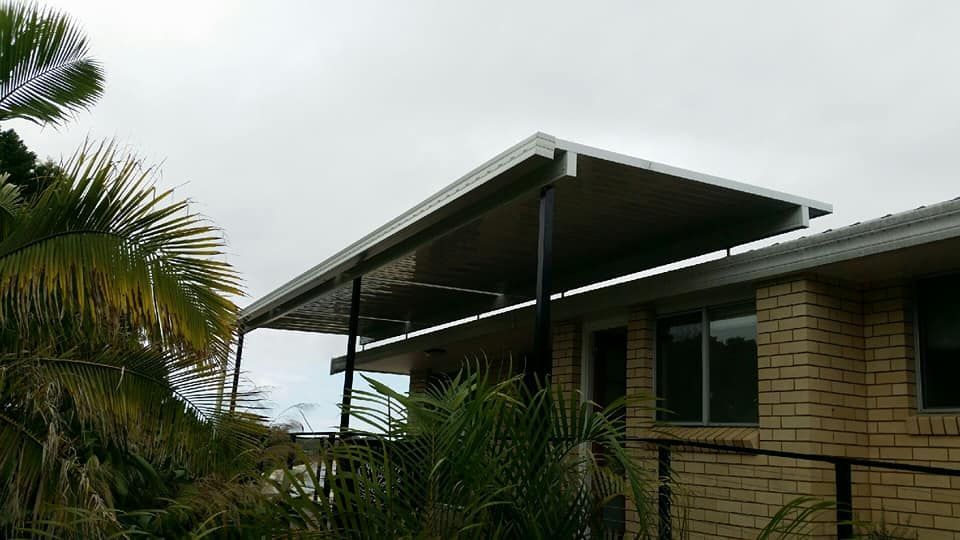 A Brick House With A Covered Porch And Palm Trees In Front Of It — Boambee Home Improvements in Sawtell, NSW