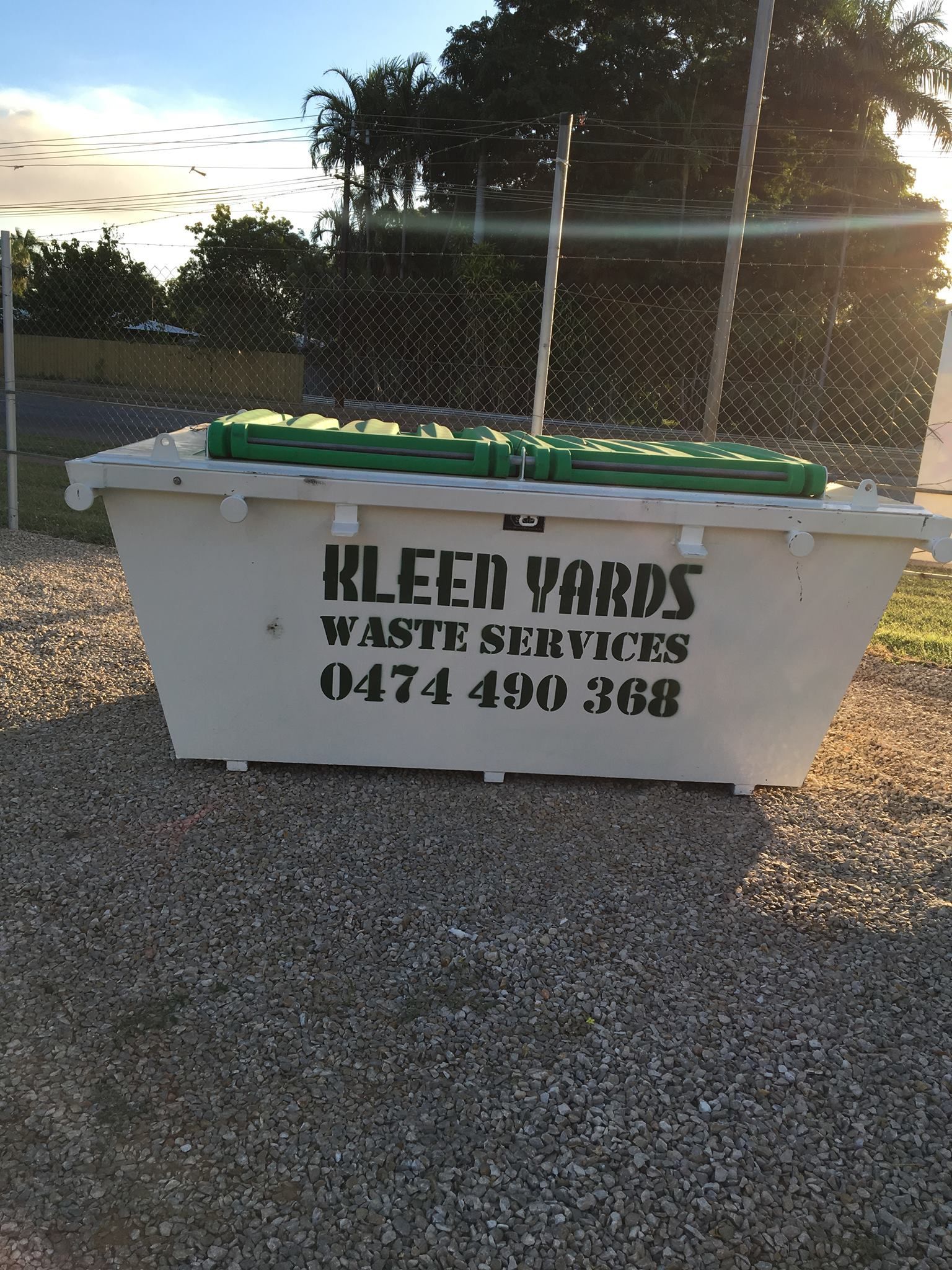 A White Skip Bin With Two Green Boxes In It — KYK Industries in Katherine, NT
