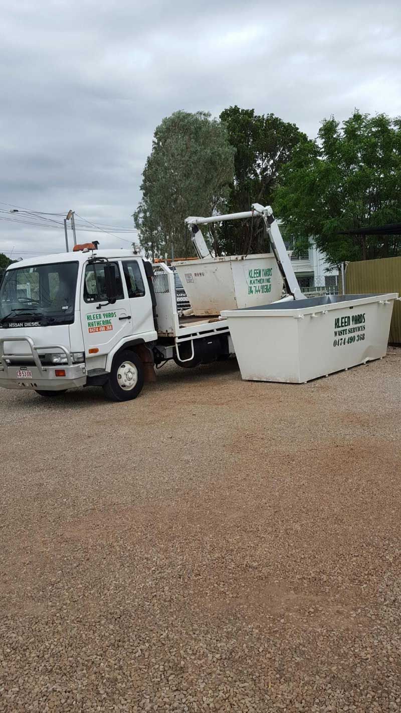 A Dumpster is Sitting Next to a Truck in a Gravel Lot — KYK Industries in Katherine, NT