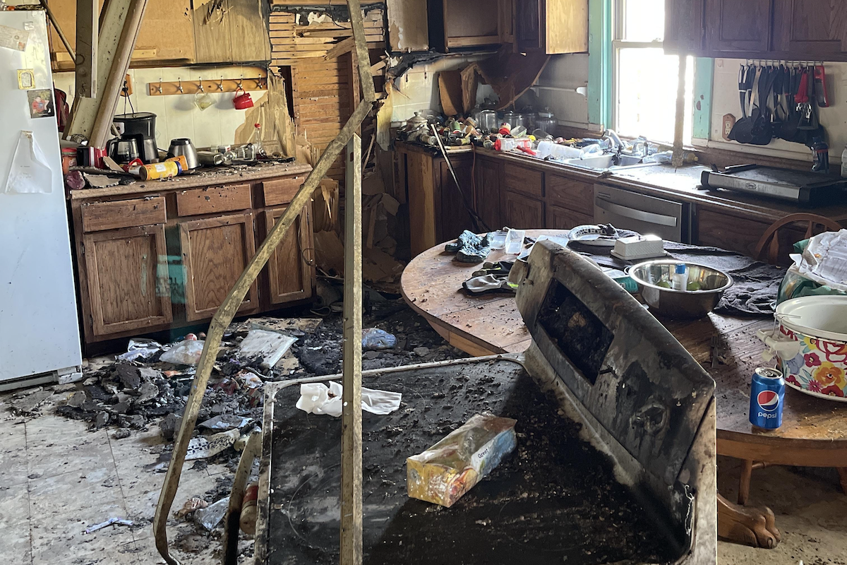 A kitchen with a broken stove and a can of pepsi on the table.