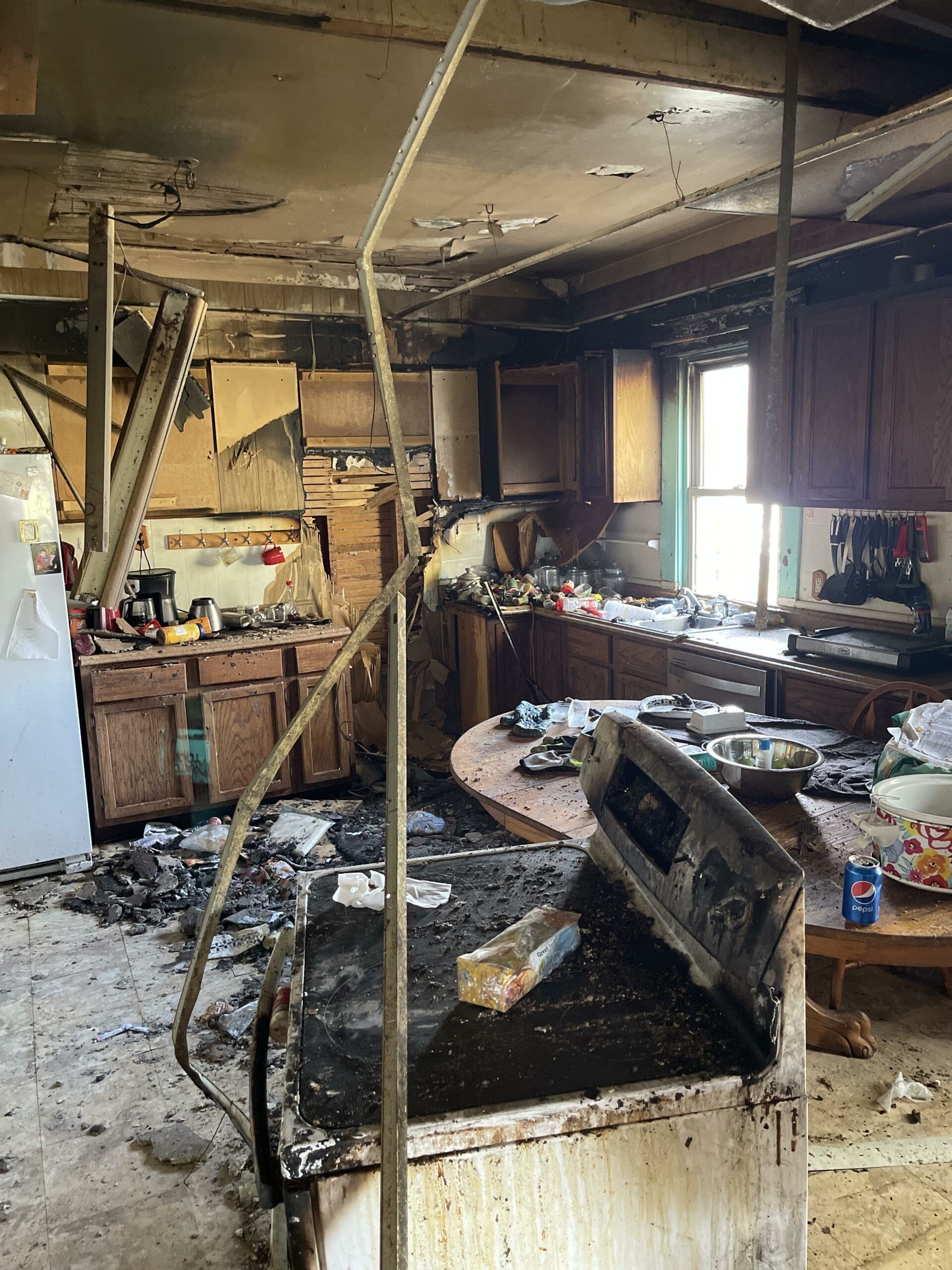 A kitchen in an abandoned house with a broken stove top oven.