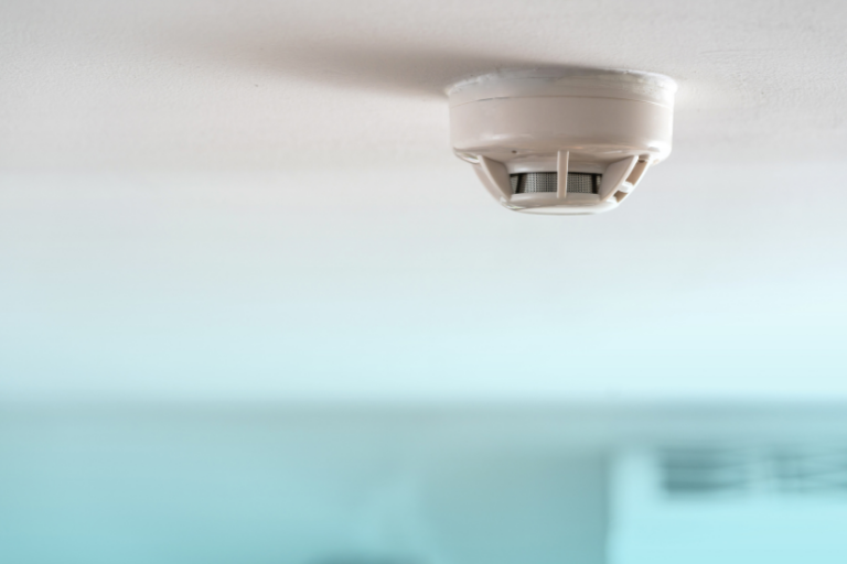 A smoke detector is mounted to the ceiling of a room.