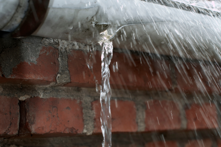 Water is leaking from a pipe on a brick wall.