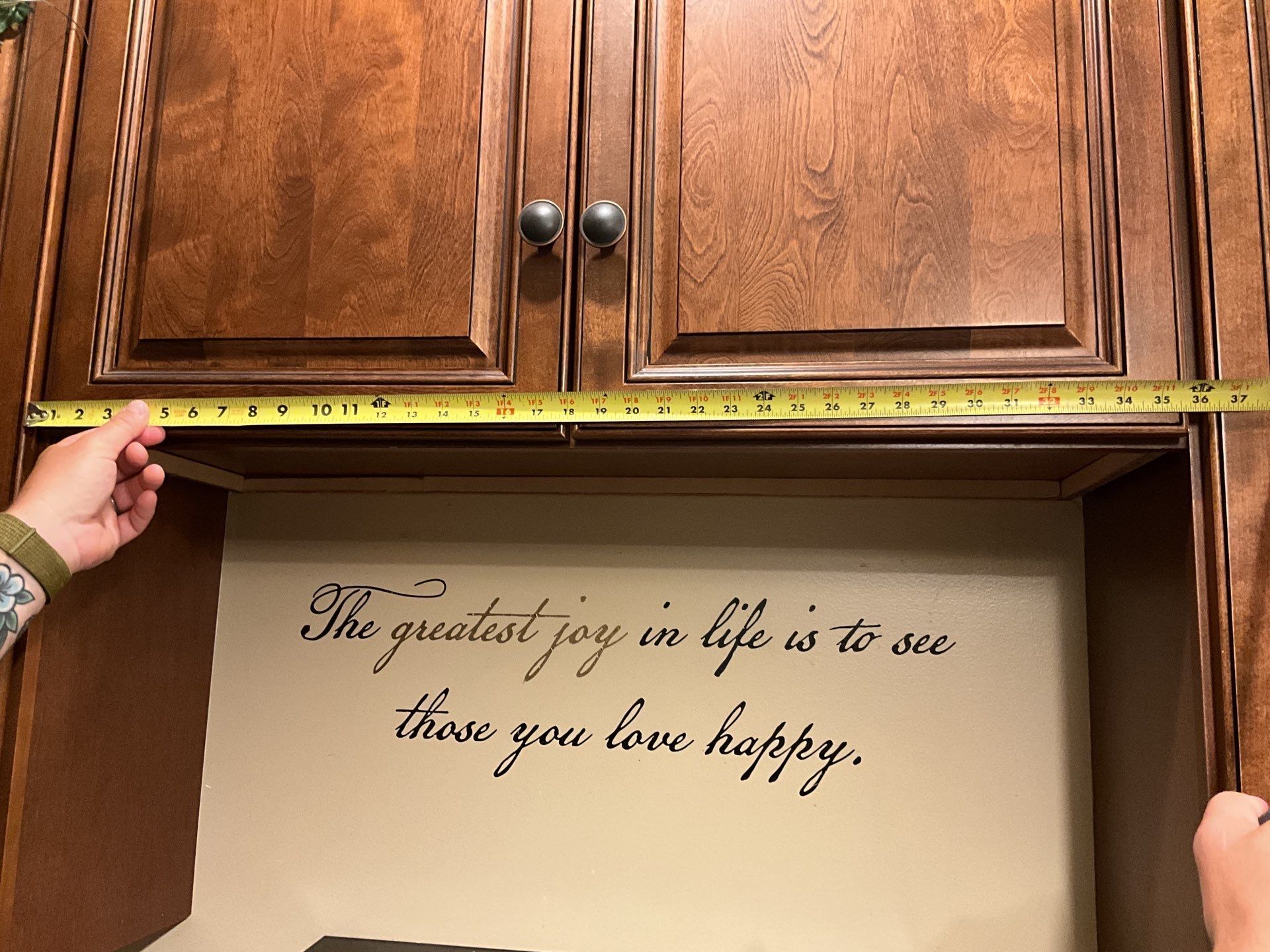 A person measuring a cabinet with a quote on it that says the greatest joy in life is to see those you love happy