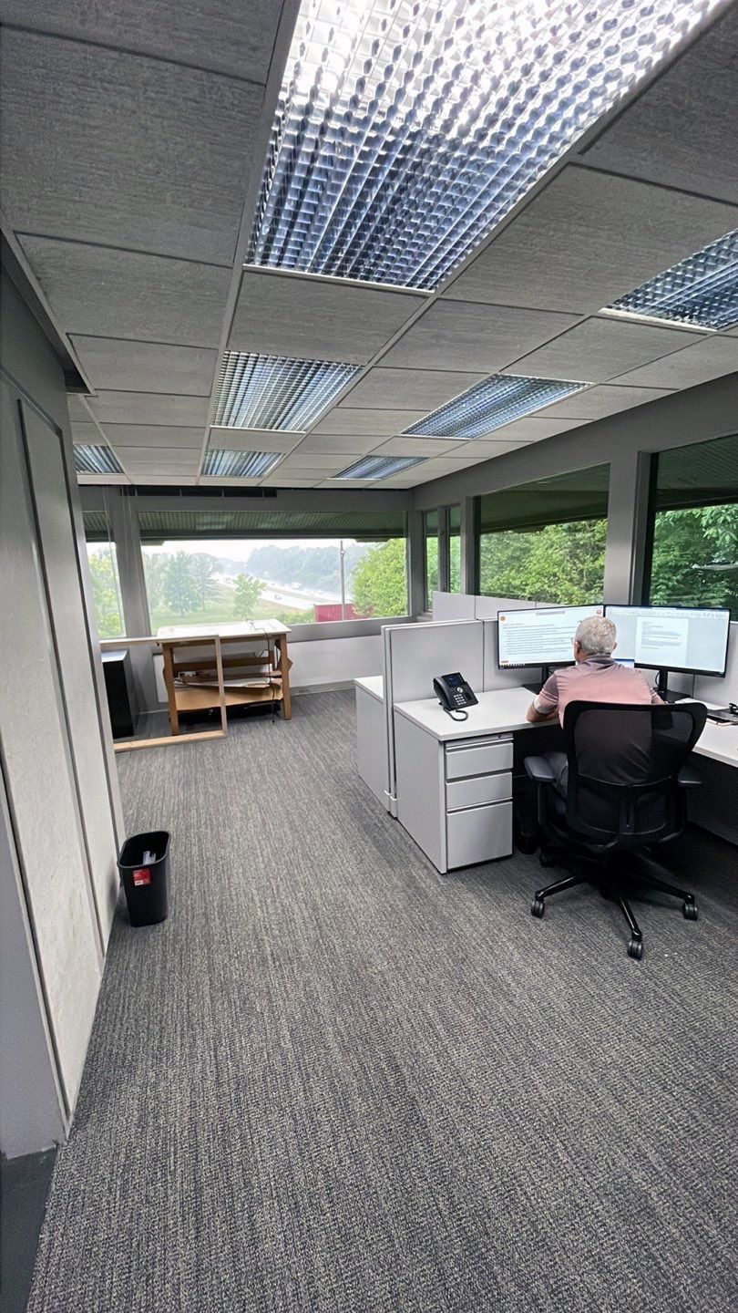 A man is sitting at a desk in an office cubicle.