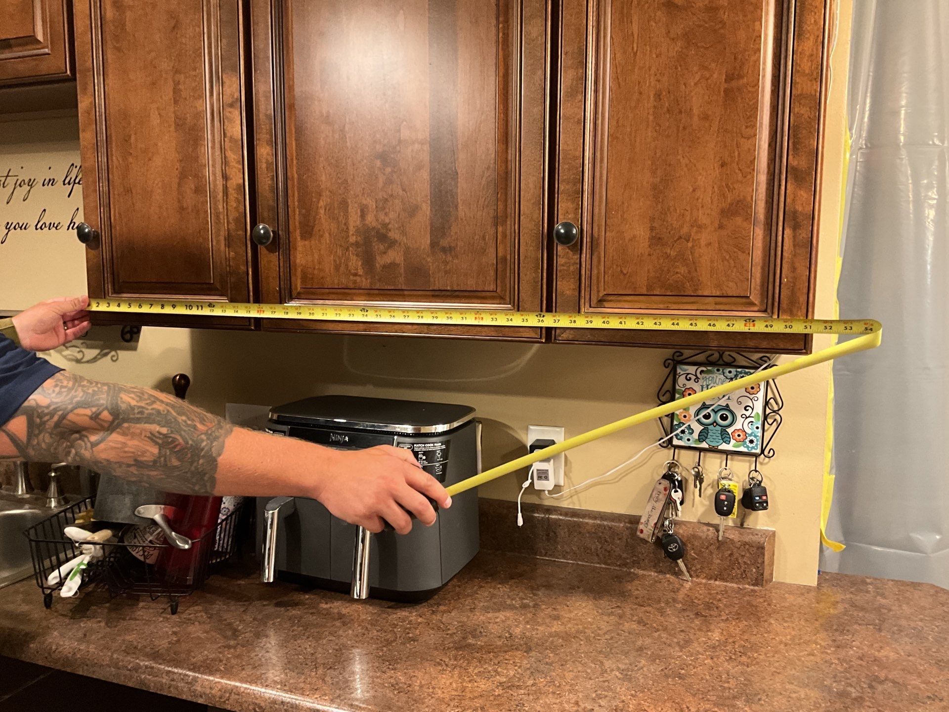 A man is measuring a kitchen counter with a tape measure.