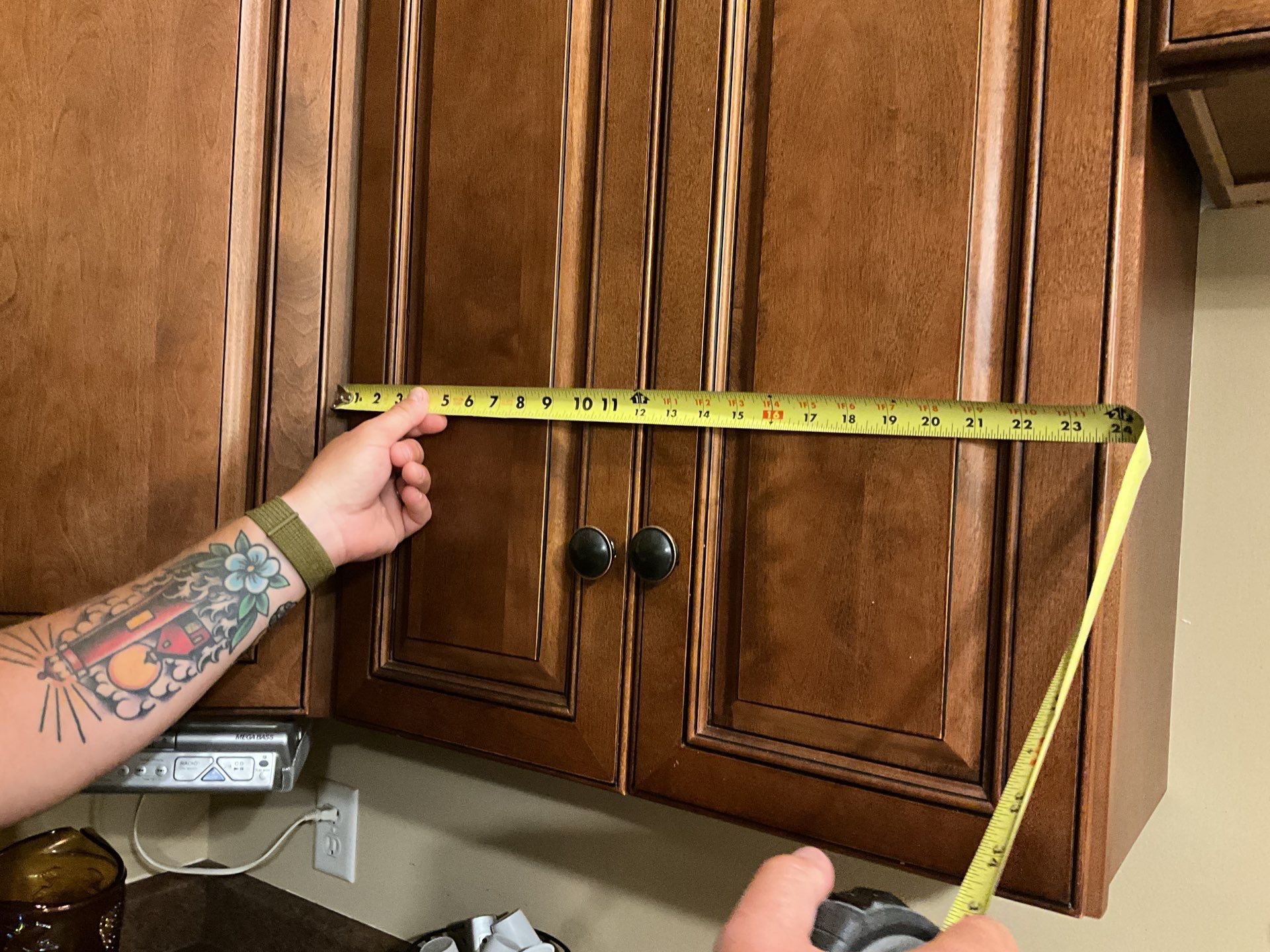 A person is measuring a cabinet with a tape measure