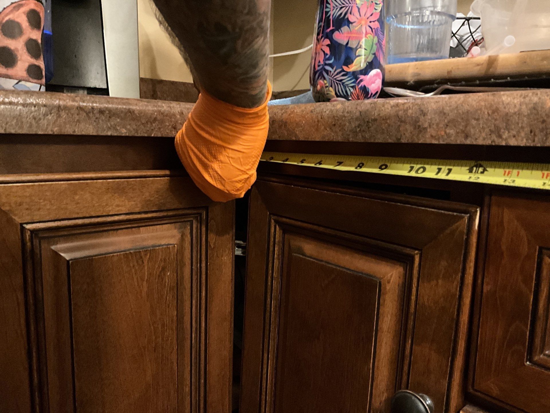 A person is measuring a cabinet with a tape measure.