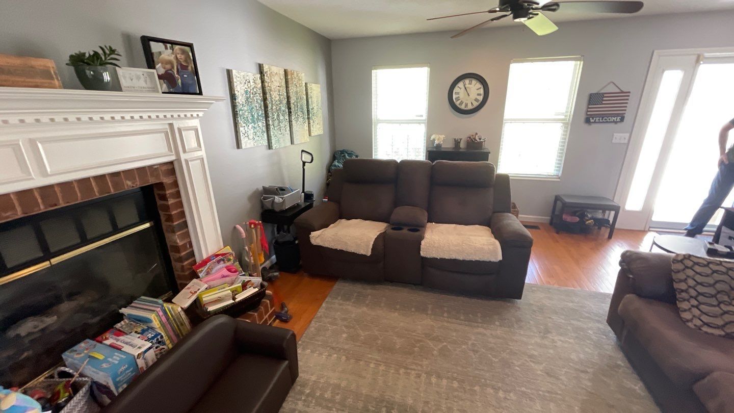 A living room with two couches , a fireplace and a clock on the wall.