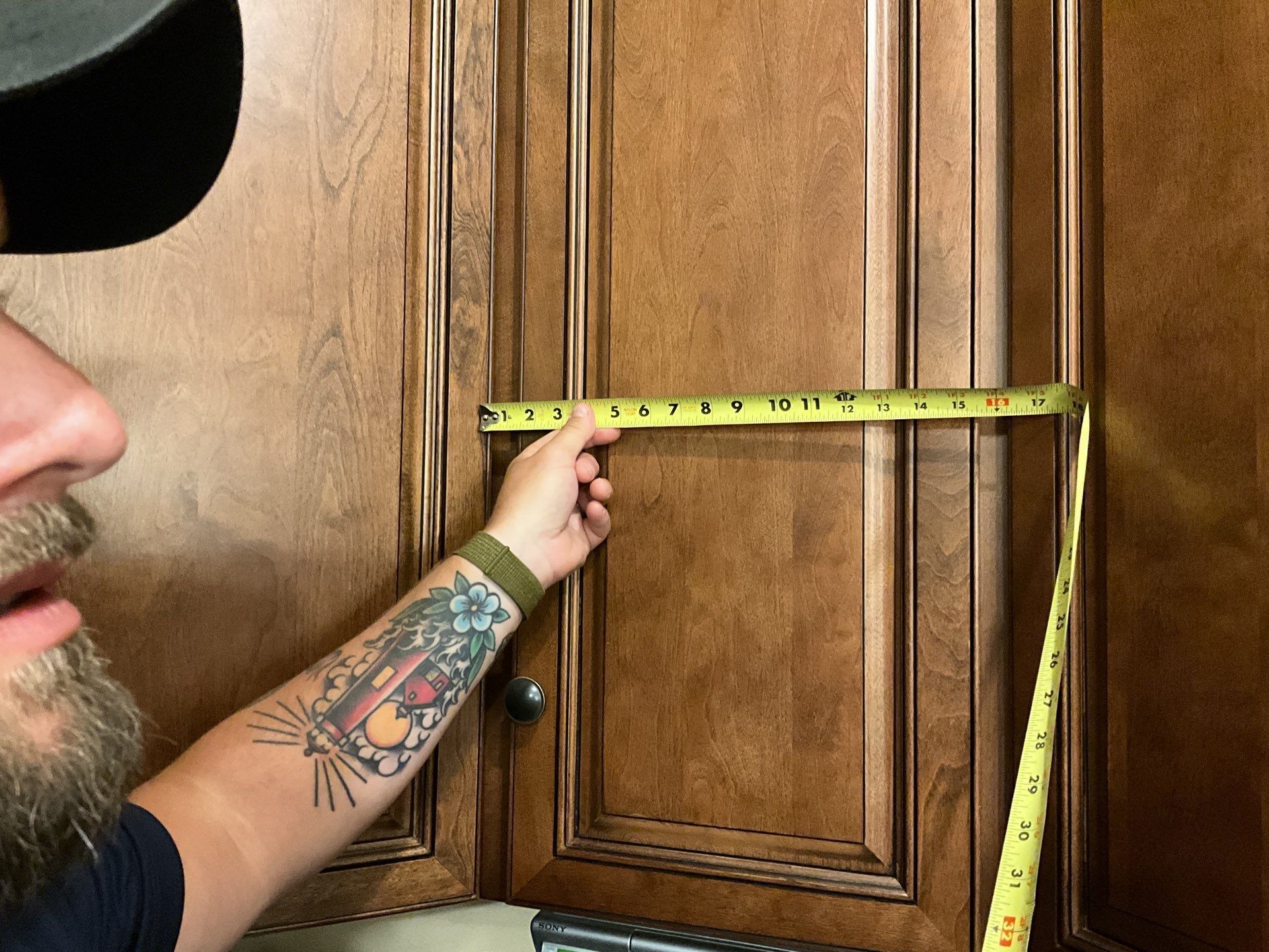 A man measuring a cabinet with a tape measure
