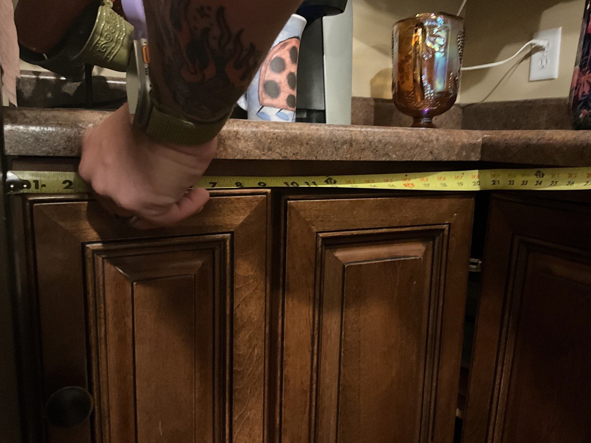 A person measuring a cabinet with a tape measure