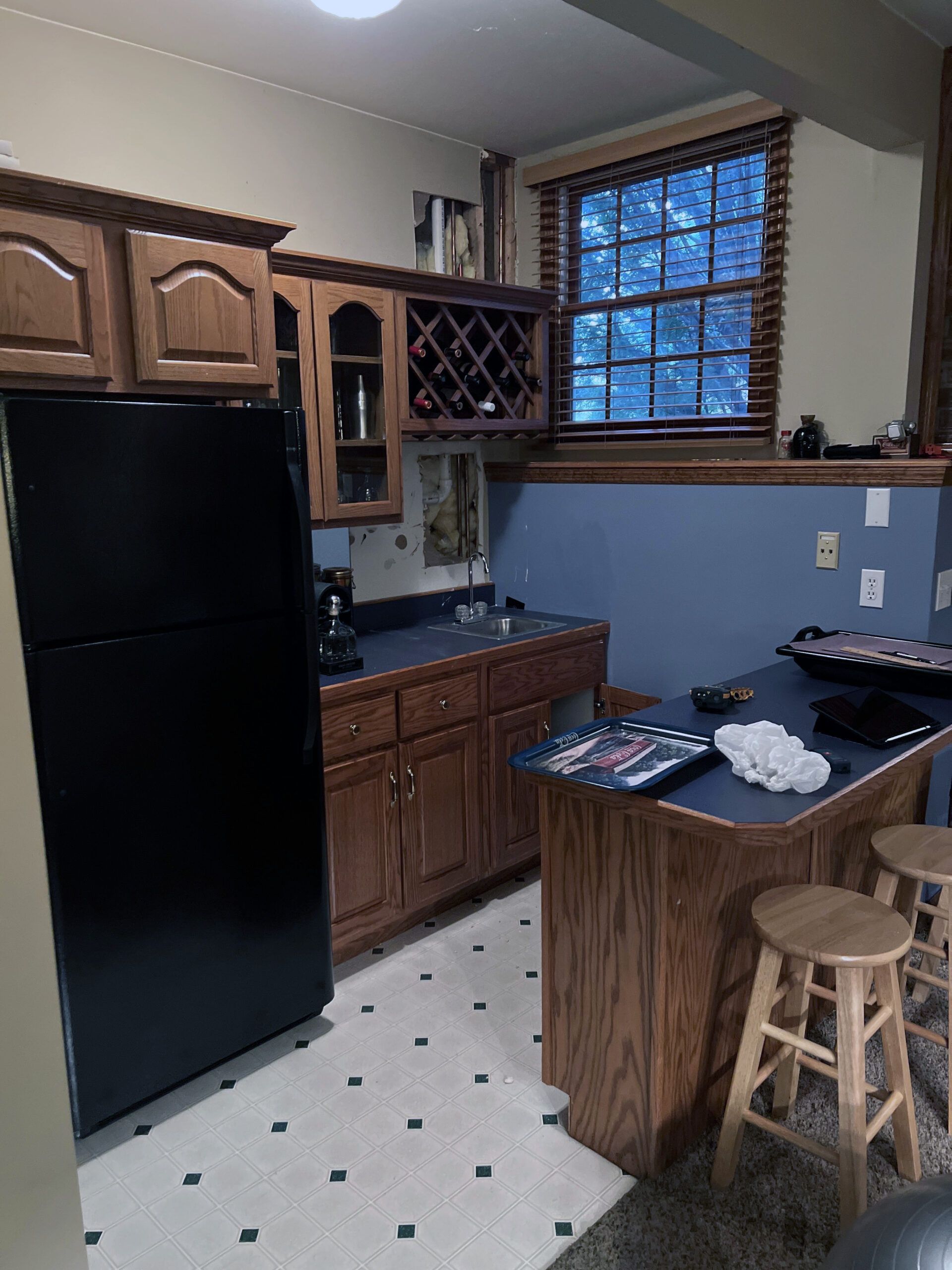 A kitchen with a black refrigerator and wooden cabinets