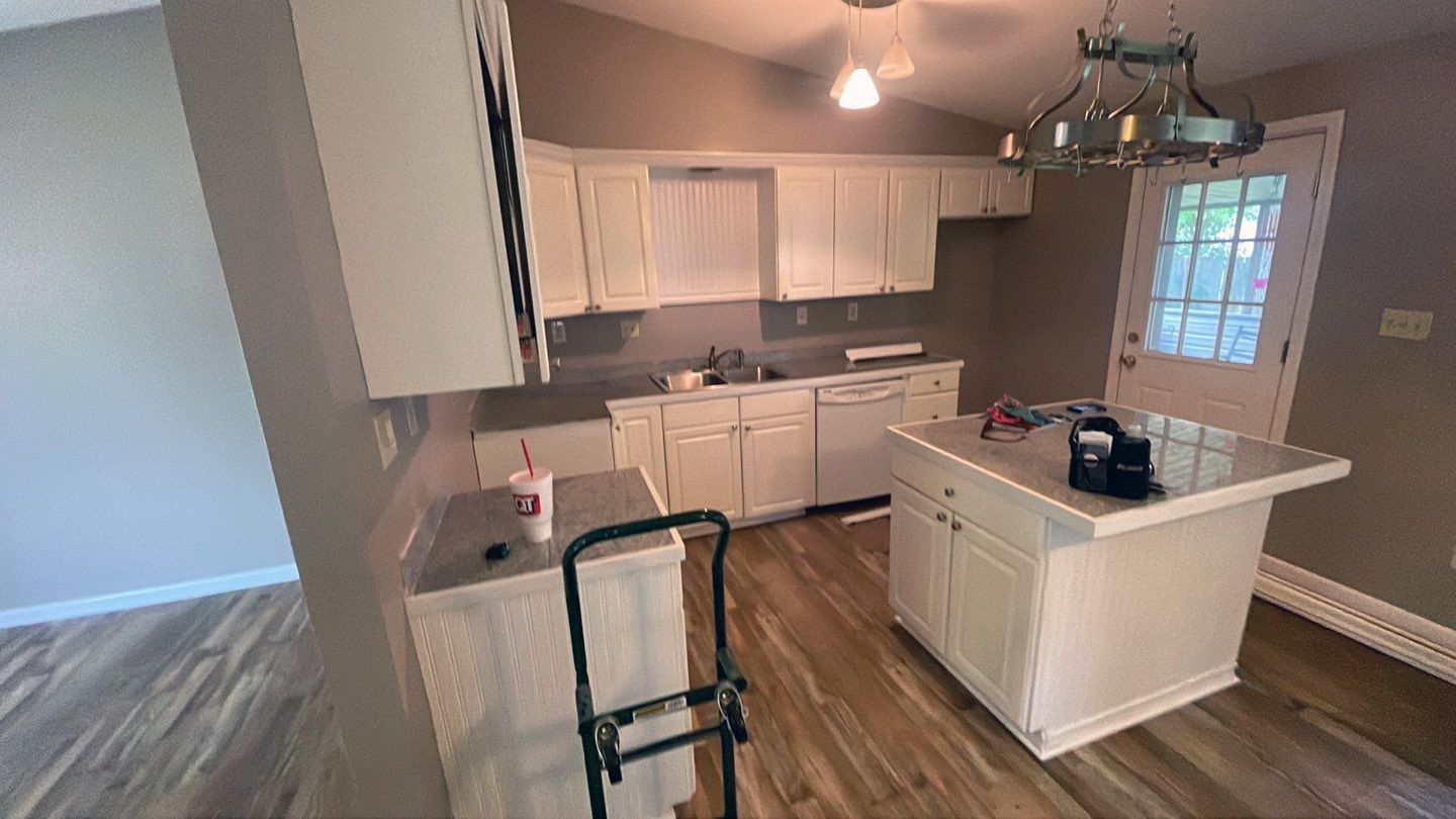 A kitchen with white cabinets and a large island in the middle of the room.