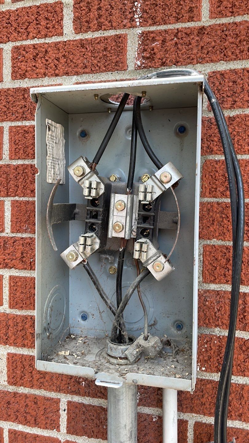 A dirty electrical box is sitting on a brick wall.