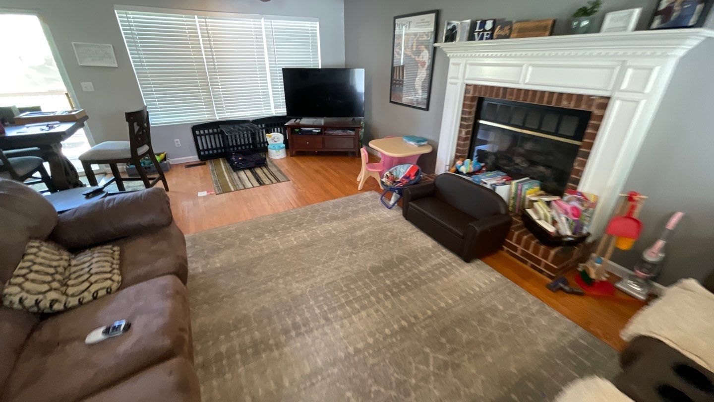 A living room with a couch , chair , television and fireplace.