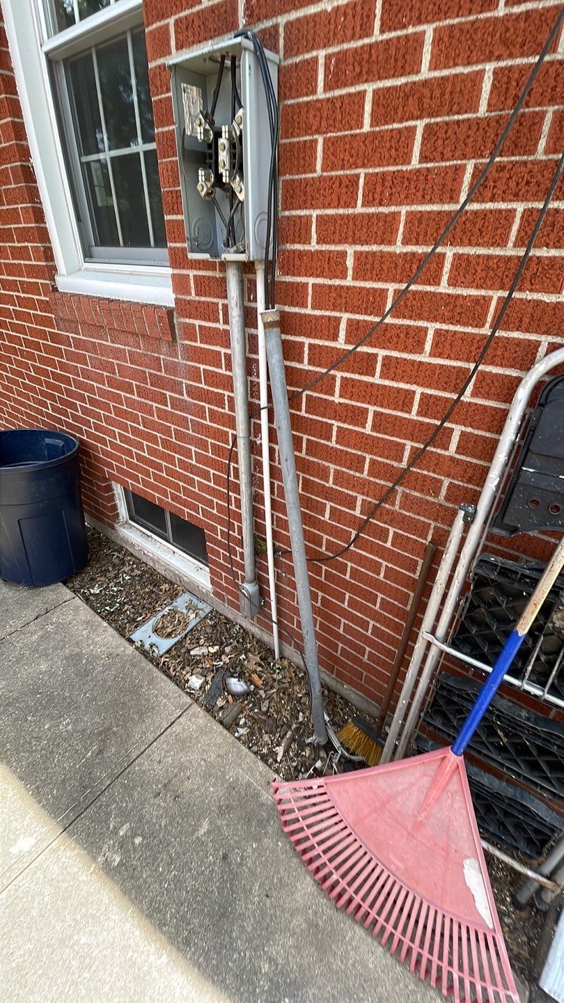 A red rake is sitting on the sidewalk in front of a brick building.