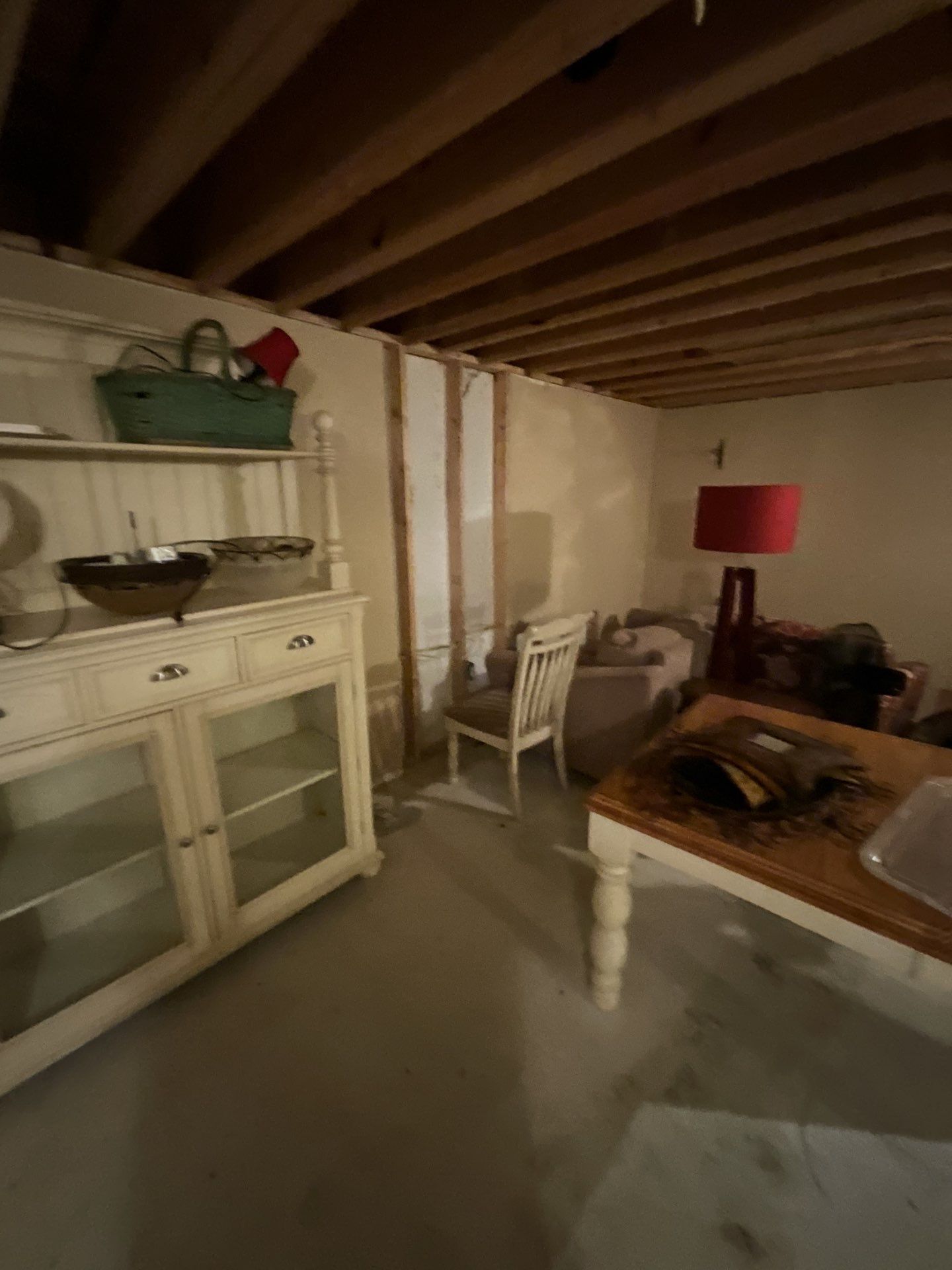 A living room with a dresser , table , chairs and a lamp.