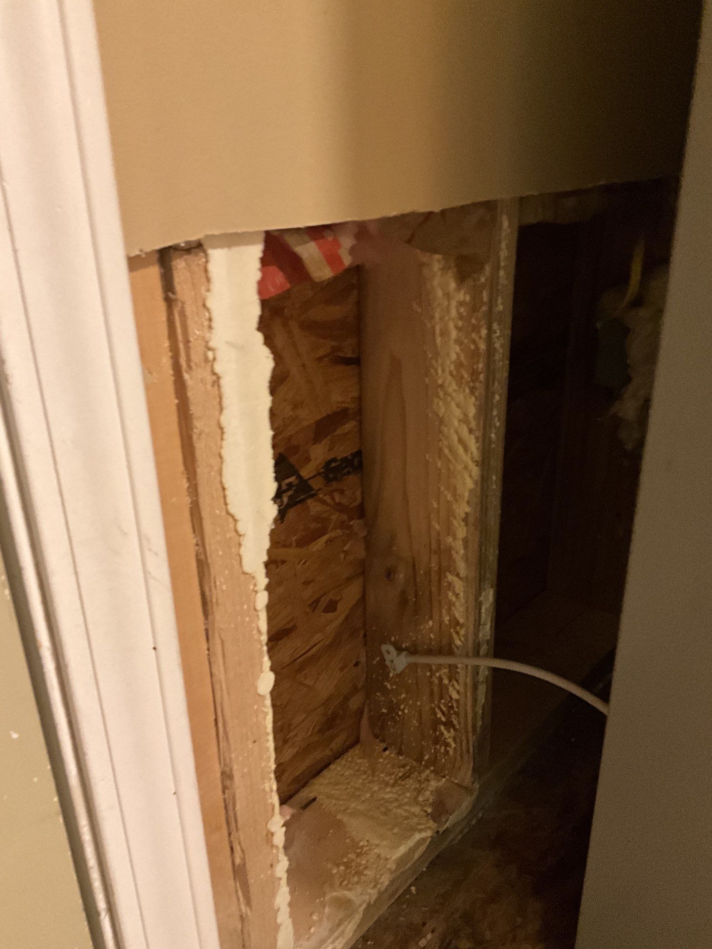 A hole in a wall with a wire sticking out of it.