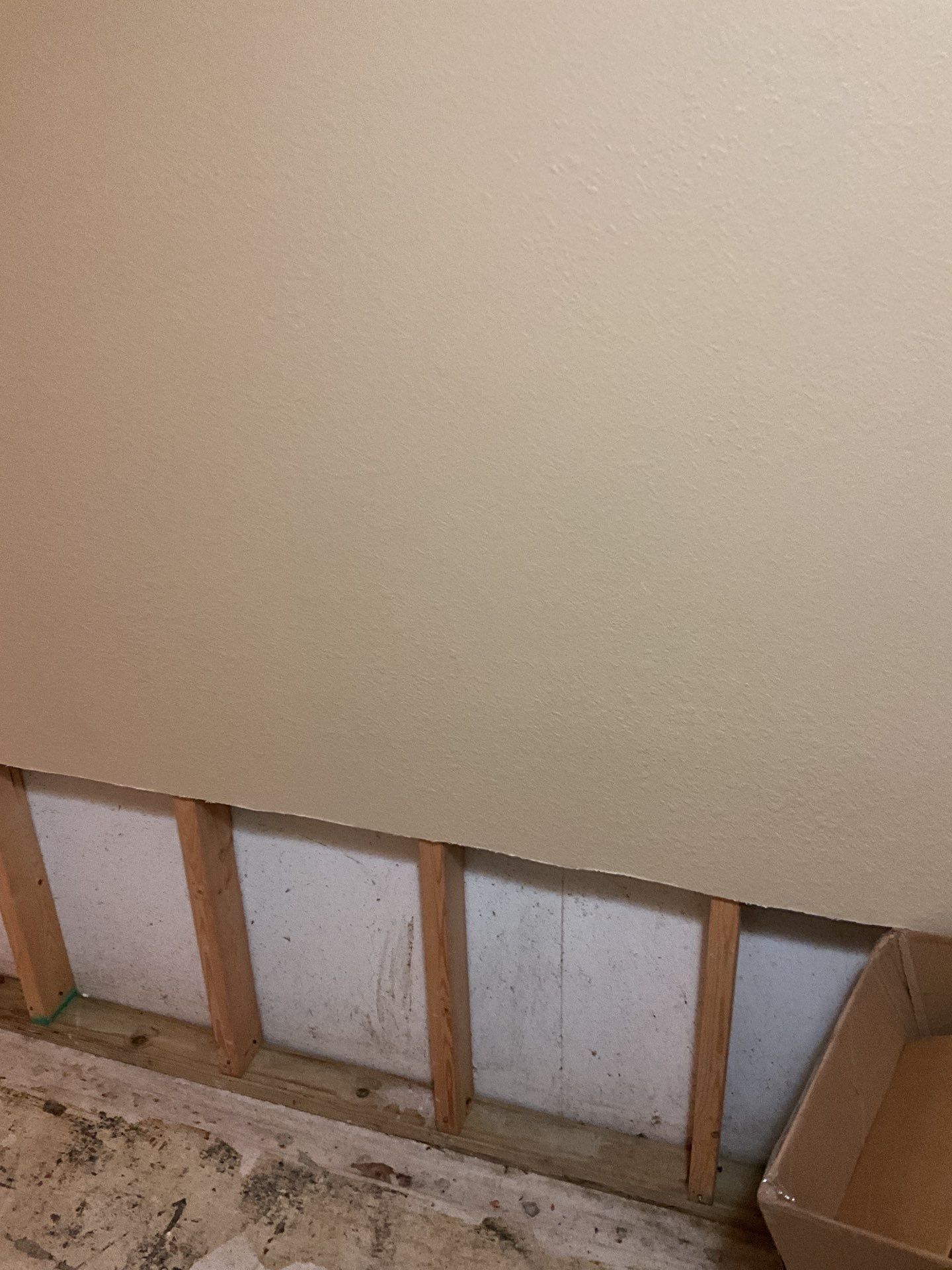 A wall with wooden beams and a box on the floor.