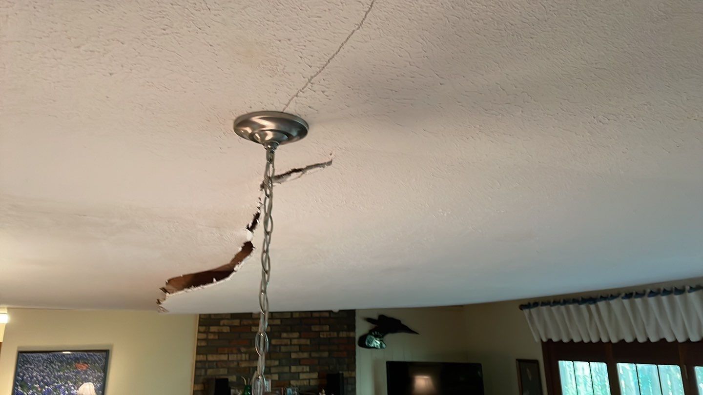 A broken light fixture is hanging from the ceiling in a living room