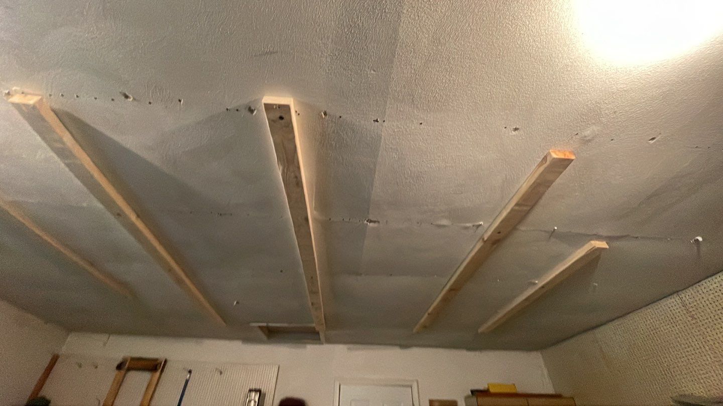 A ceiling with wooden beams hanging from it in a garage.