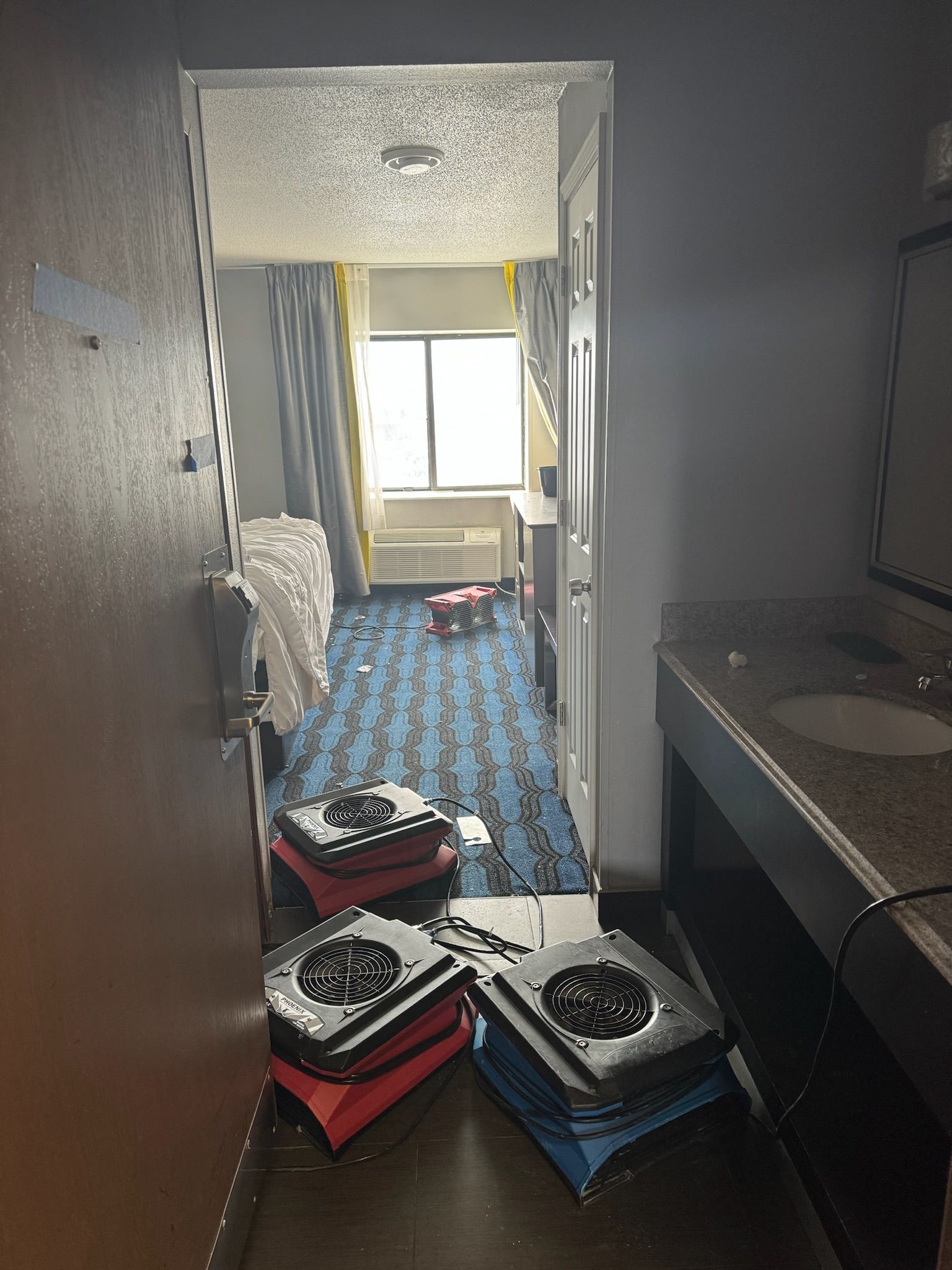 A hotel room with a sink and two fans on a table.